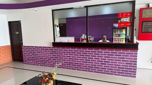A reception area with a purple brick wall, a glass counter, and a check-in kiosk. - OYO 91288 HOTEL PARADISE BATU CAVES (Selayang)