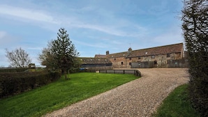 A stone building with a gravel driveway leading to a grassy area. - Host & Stay | The Grainary (Bridlington)