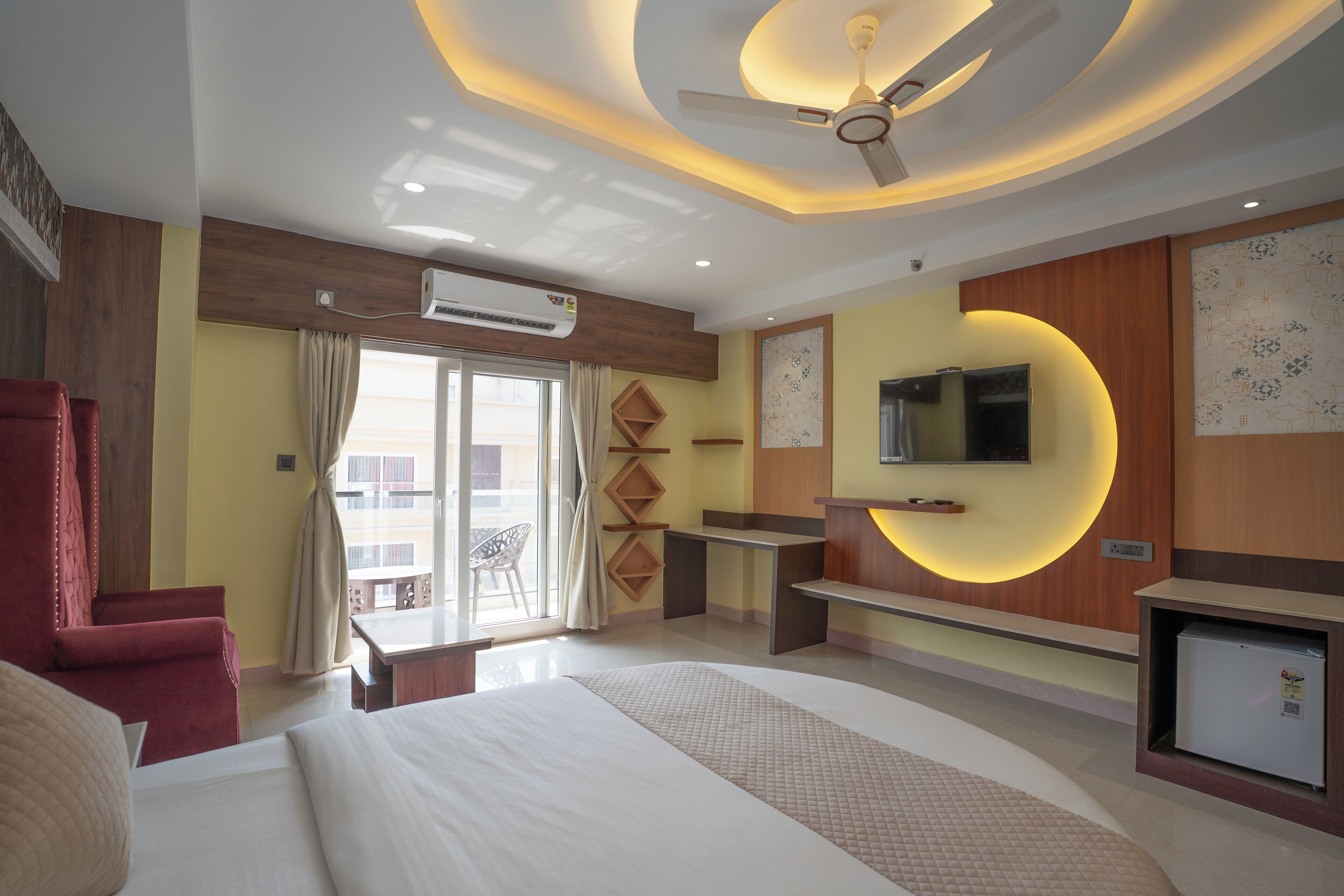 A hotel room with a large bed, a desk, a TV, and a ceiling fan.