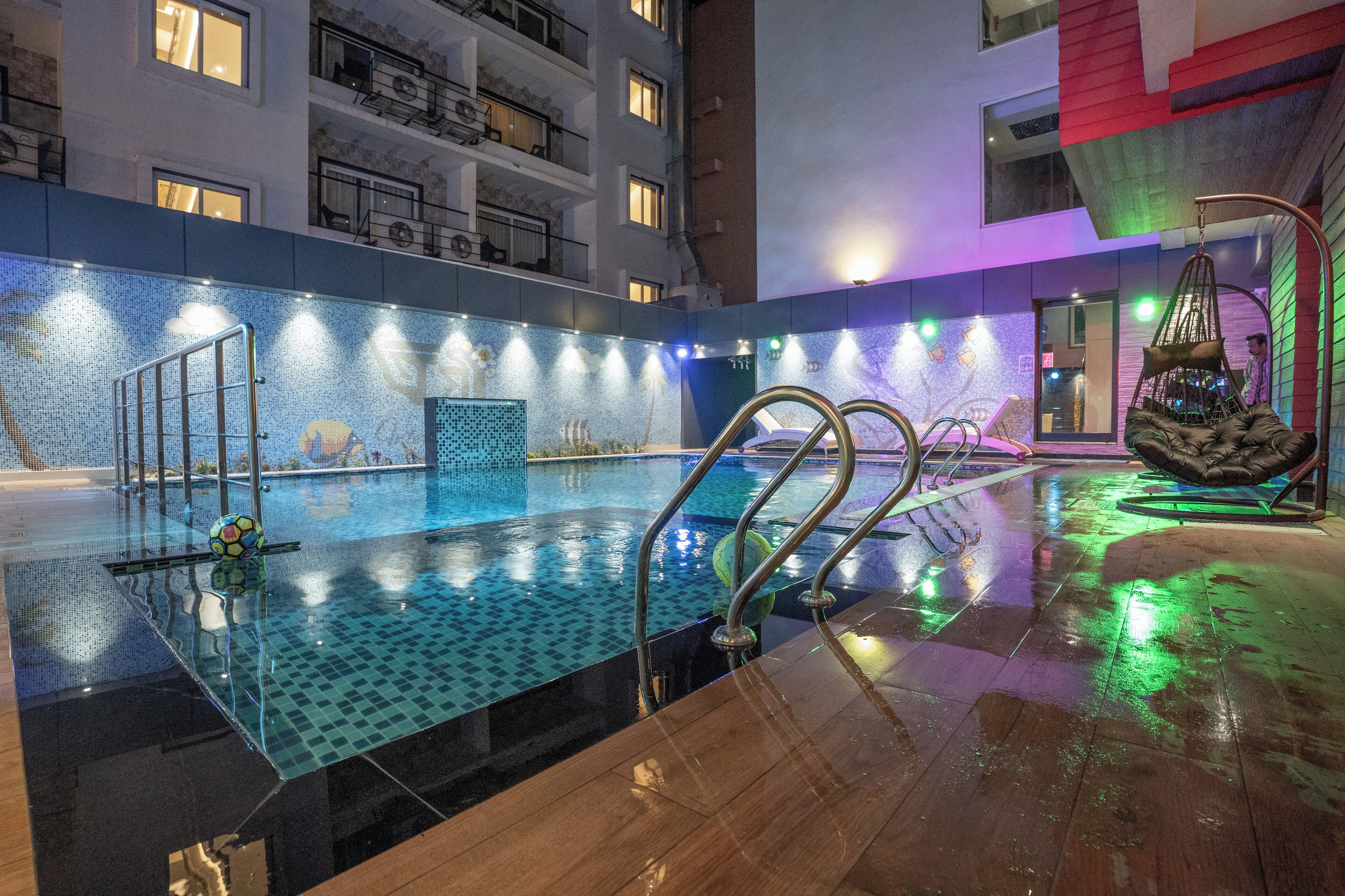 An indoor swimming pool with clear water, a tiled floor, and a metal railing.