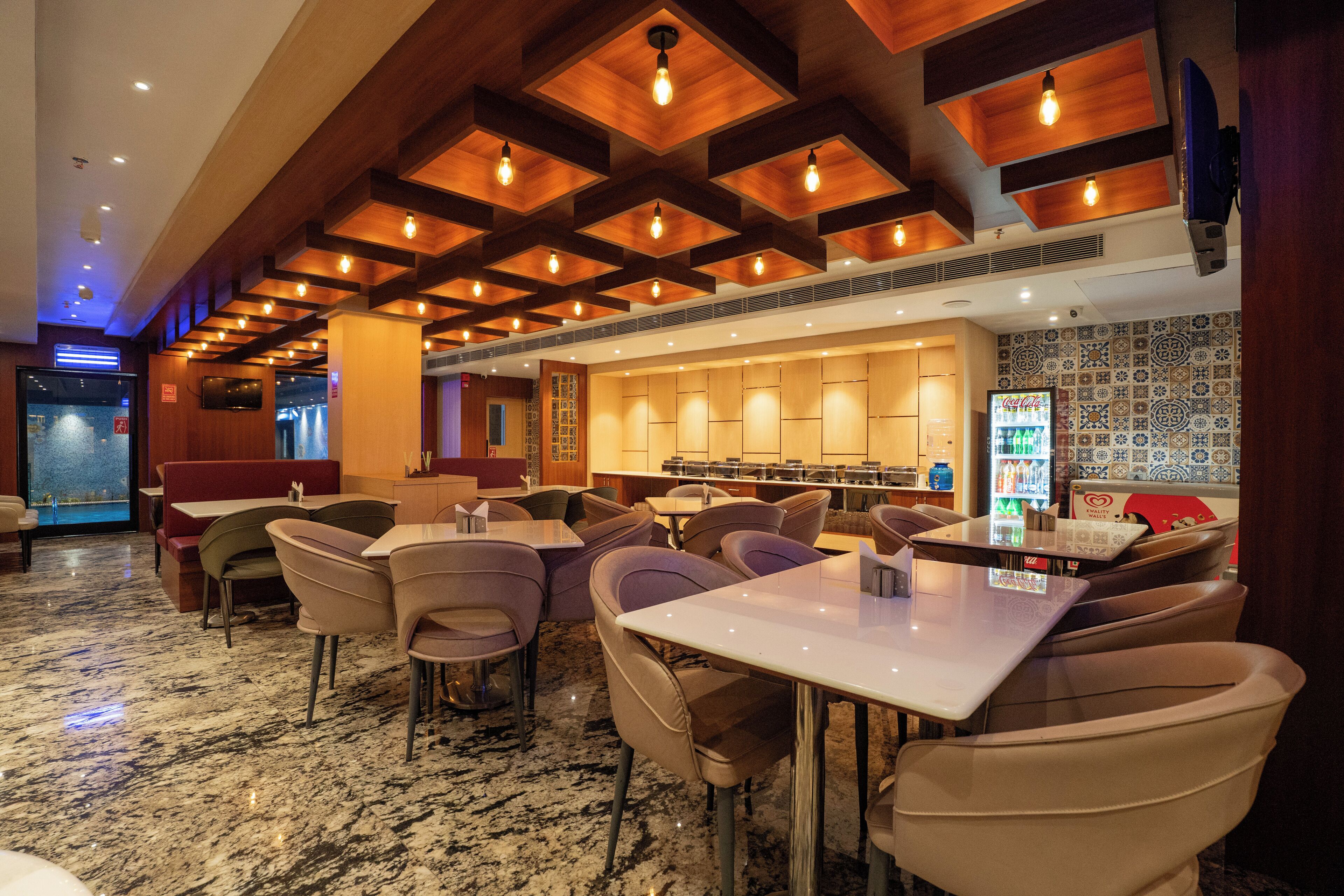 A restaurant with a modern interior, featuring wooden ceiling beams, marble flooring, and a variety of seating options including booths and tables.