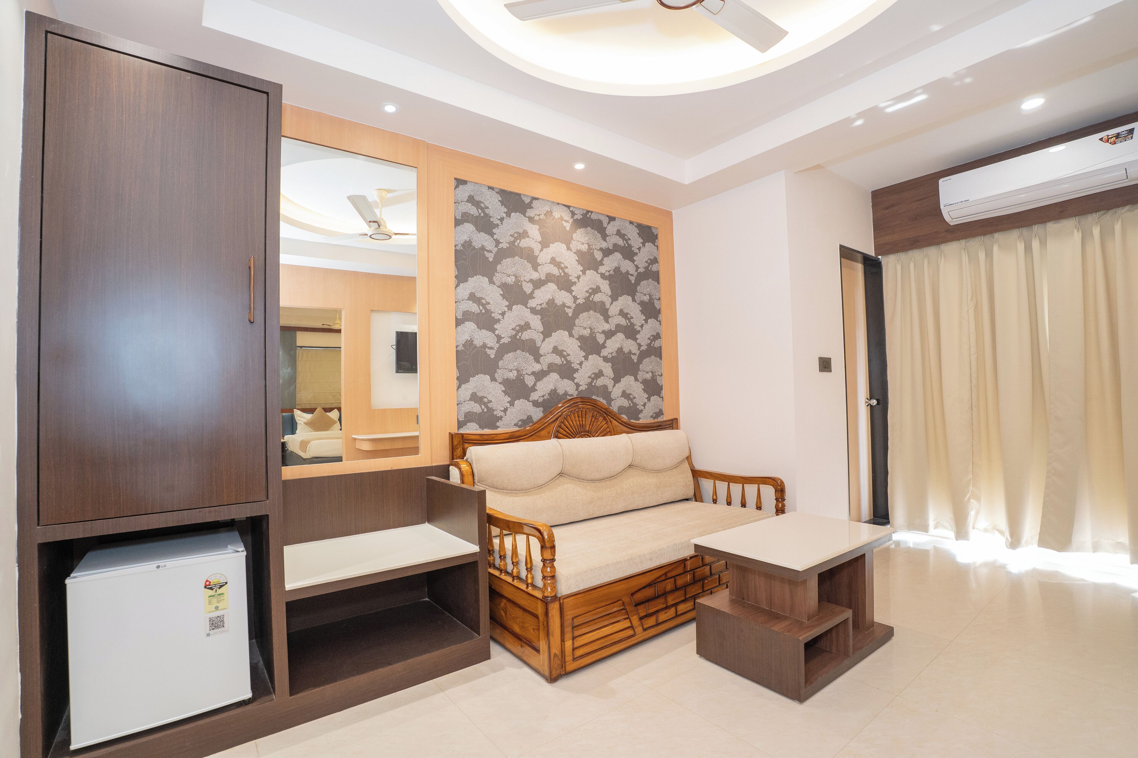 A modern hotel room with a wooden bed, a small table, a built-in wardrobe, and a ceiling fan.