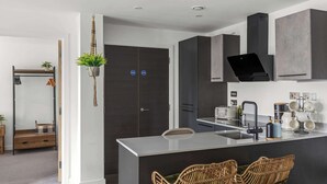 A modern kitchen with a central island, dark cabinetry, and a hanging plant. - York Retreat • Shambles • Free Parking • Gym Access (York)