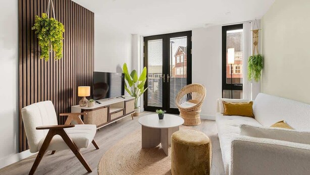 A modern living room with a sofa, armchair, round coffee table, and a TV. - City Gate York • Gym • Parking • Walk to Minster (York)