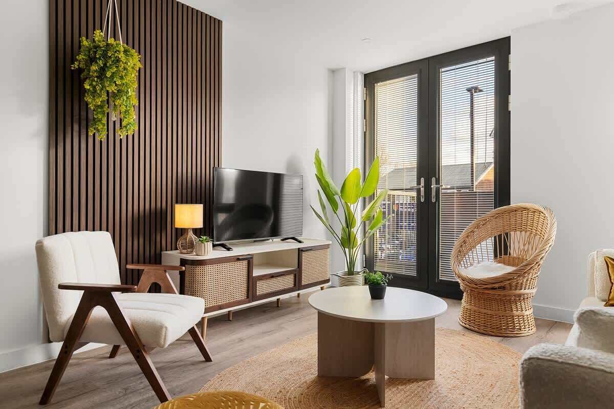 Una sala de estar moderna con televisor, sofá y sillones de mimbre.
