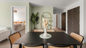 A dining area with a black table, wicker chairs, and a white vase with dried flowers. - City Gate York • Gym • Parking • Walk to Minster (York)