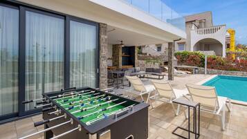 A poolside area with a foosball table, outdoor seating, and a pool.