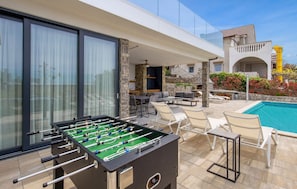 A poolside area with a foosball table, outdoor seating, and a pool. - Villa Oblica (Jakišnica)