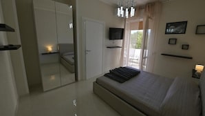 Een moderne slaapkamer met een groot bed, een aan de muur bevestigde televisie en een kroonluchter.
