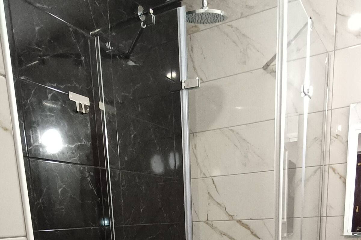 Une salle de bain comprenant des toilettes, une douche fermée par une paroi de verre et un lavabo.