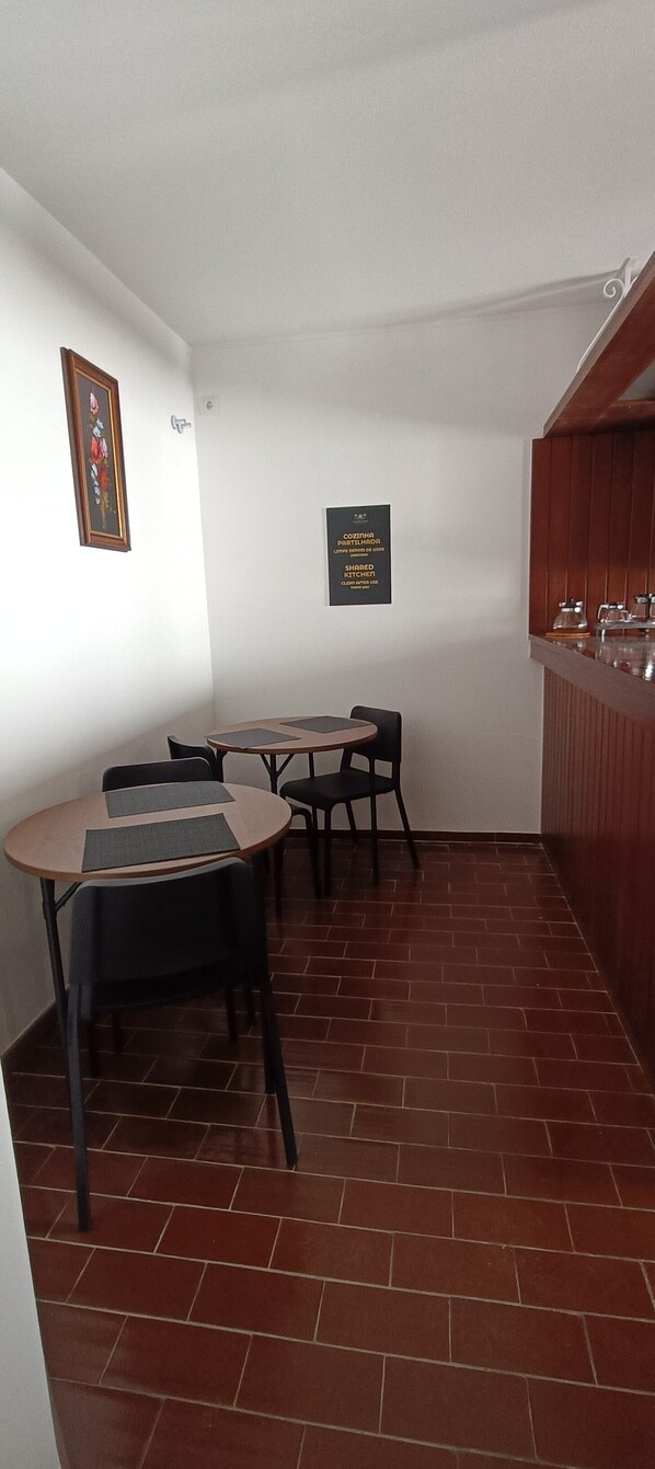 A dining area with a table and chairs, a kitchen counter, and a sign indicating a shared kitchen. - Villa Golden Coast -Lagos (Lagos)