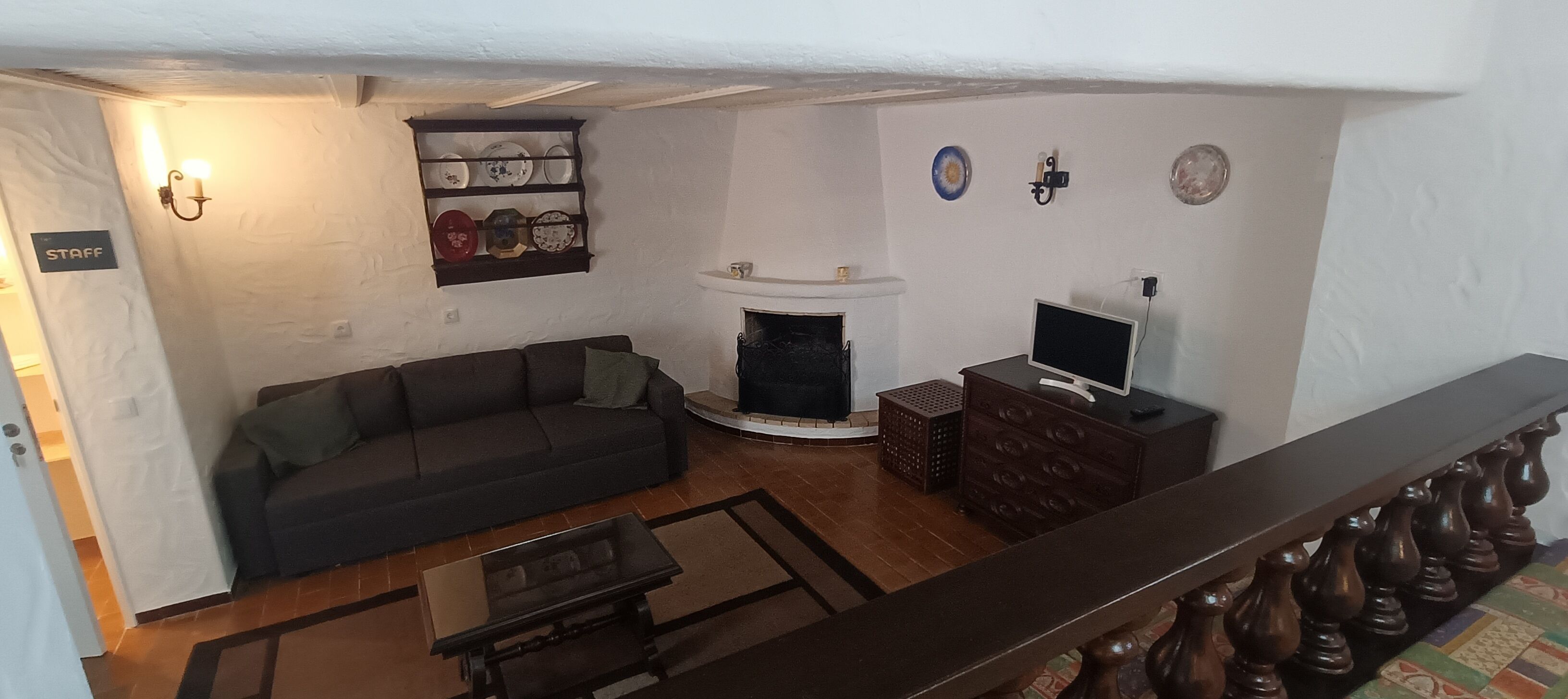 A living room with a sofa, a fireplace, a TV, and a staircase.