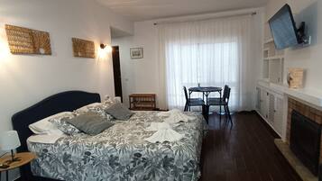 Un dormitorio con cama, mesita de noche, lámpara y televisor montado en la pared.