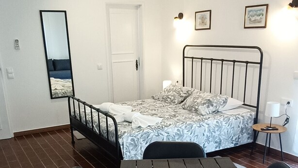 A room with a bed, a table with chairs, a mirror, and a door. - Villa Golden Coast -Lagos (Lagos)