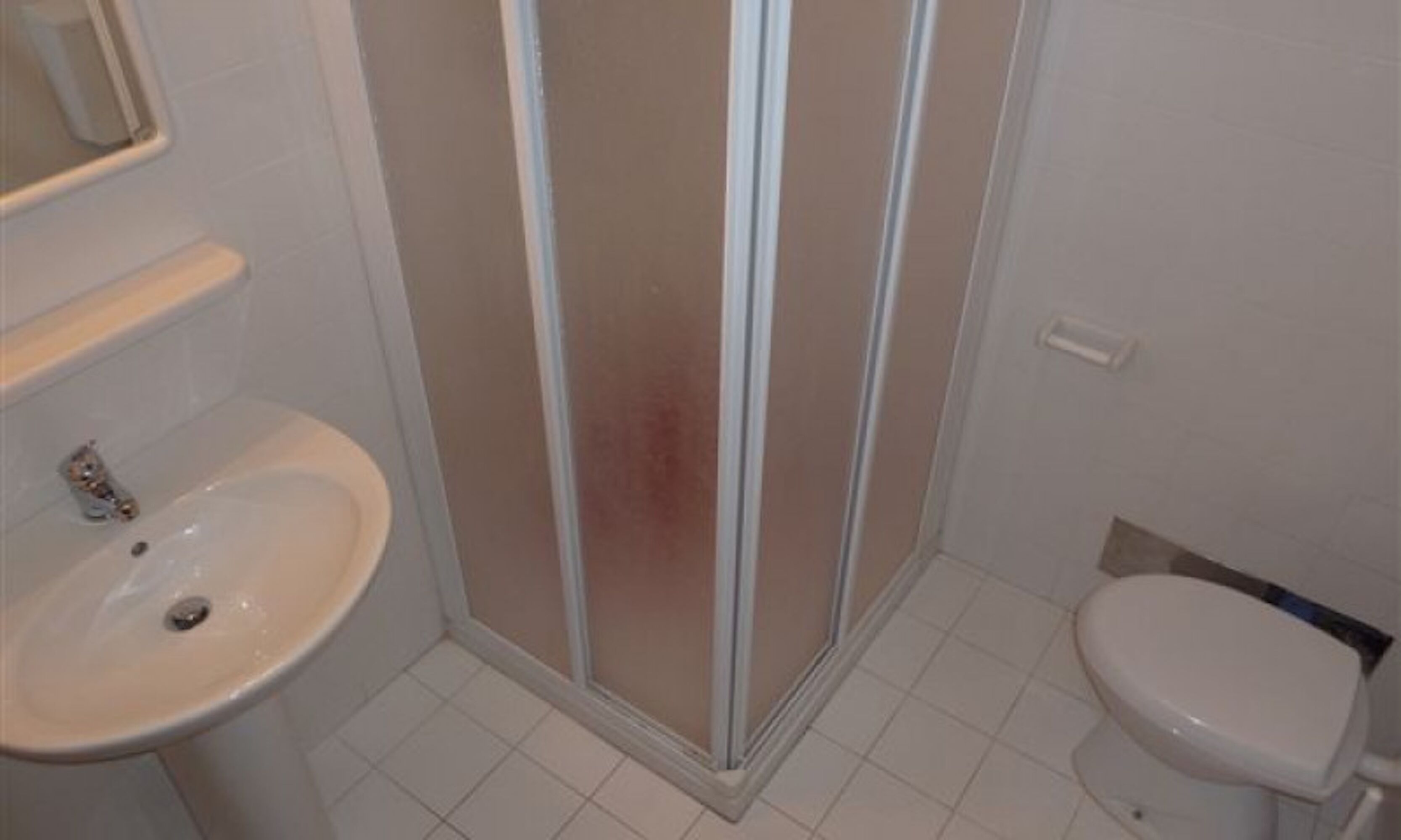 Un bagno con lavandino, WC e cabina doccia in vetro.