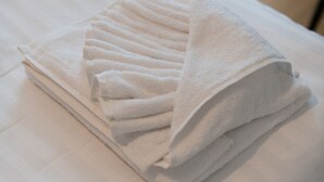 A neatly folded white towel on a bed with a wooden floor. - LIV - Comfortable Athens Studio S8-2c (Athens)