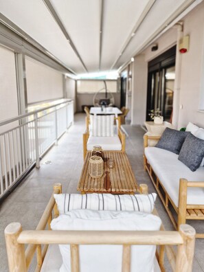 A covered outdoor seating area with wooden furniture and a central table. - Urban quality comfort (Thessaloniki)
