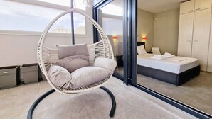 Et moderne værelse med en hængestol, seng og stort vindue.