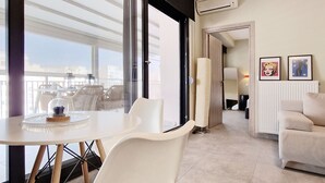 En moderne stue med en hvid sofa, et spisebord med stole, og et stort vindue med udsigt.