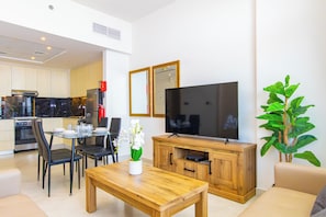 A modern living room with a flat-screen TV, wooden coffee table, and a dining area with chairs and a table. - Bloomfields 1BR - Binghatti Avenue - Jaddaf (Dubai)