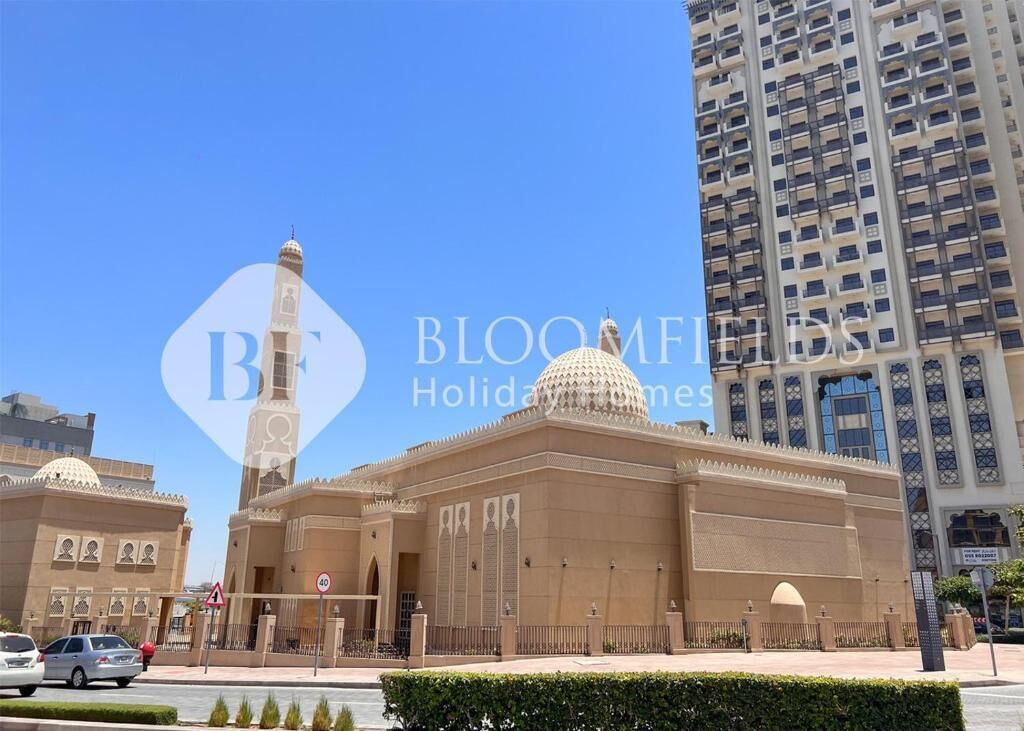 A large mosque with a prominent dome and minaret, surrounded by modern high-rise buildings.
