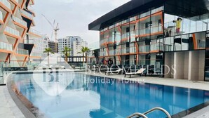 Un hotel moderno con piscina, facciata in vetro e vista sullo skyline della città.