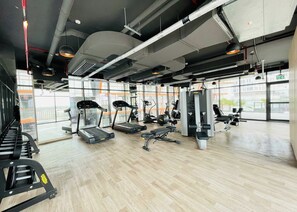 A gym with treadmills, weight machines, and a large window. - Bloomfields 1BR - Binghatti Avenue - Jaddaf (Dubai)