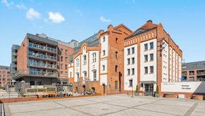 Een modern gebouw met gevels van baksteen en glas, een binnentuin met zitplaatsen en een bord voor Browar Lechus.