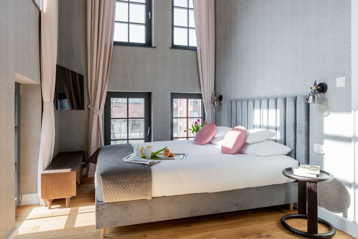 Un dormitorio moderno con una cama grande, una mesita de noche y una ventana con cortinas.