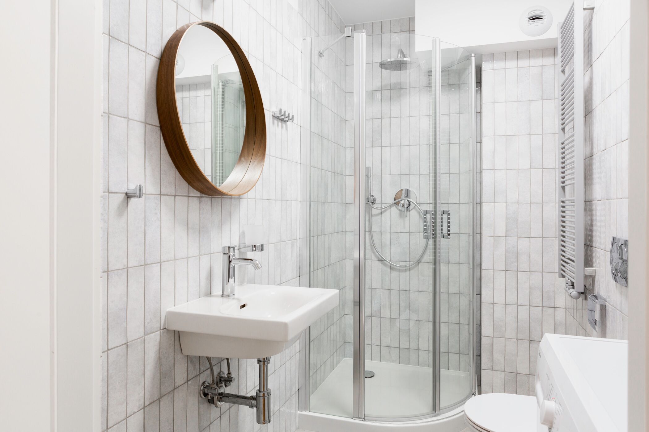A modern bathroom with a glass-enclosed shower, a white sink, and a toilet.