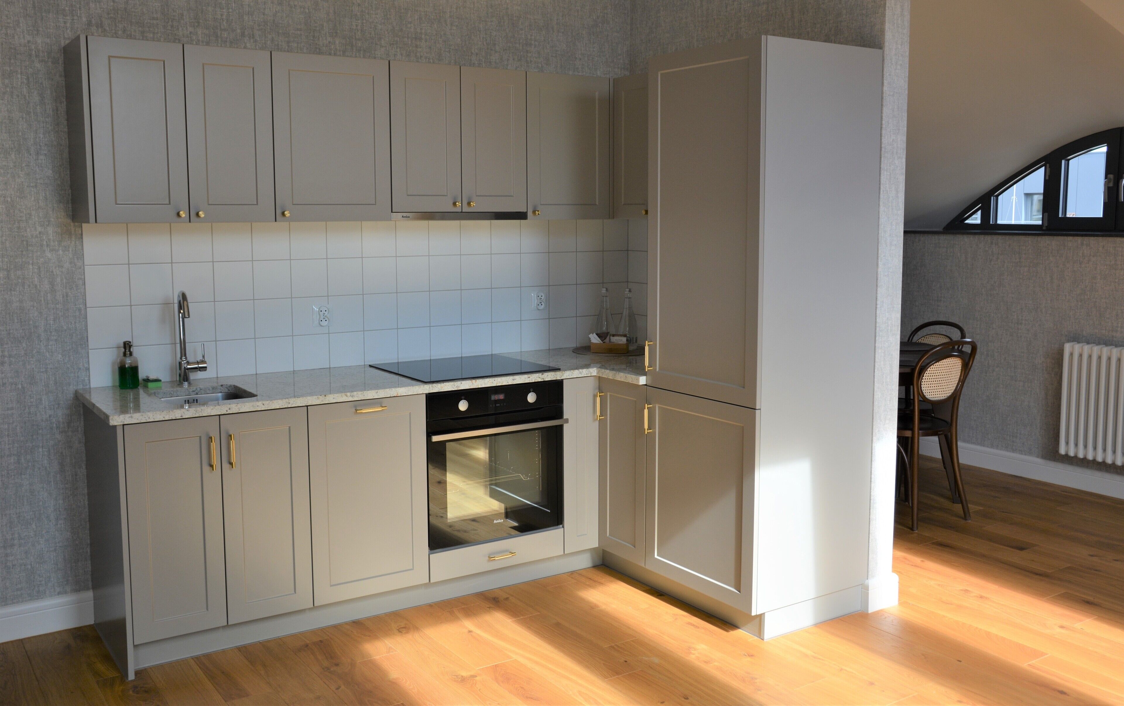 A kitchen with grey cabinets, a black stove, and a white refrigerator.
