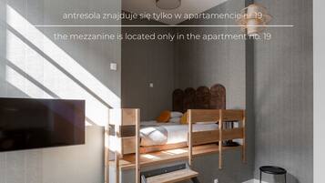 A bedroom with a bunk bed, a TV mounted on the wall, and a small table with a magazine.