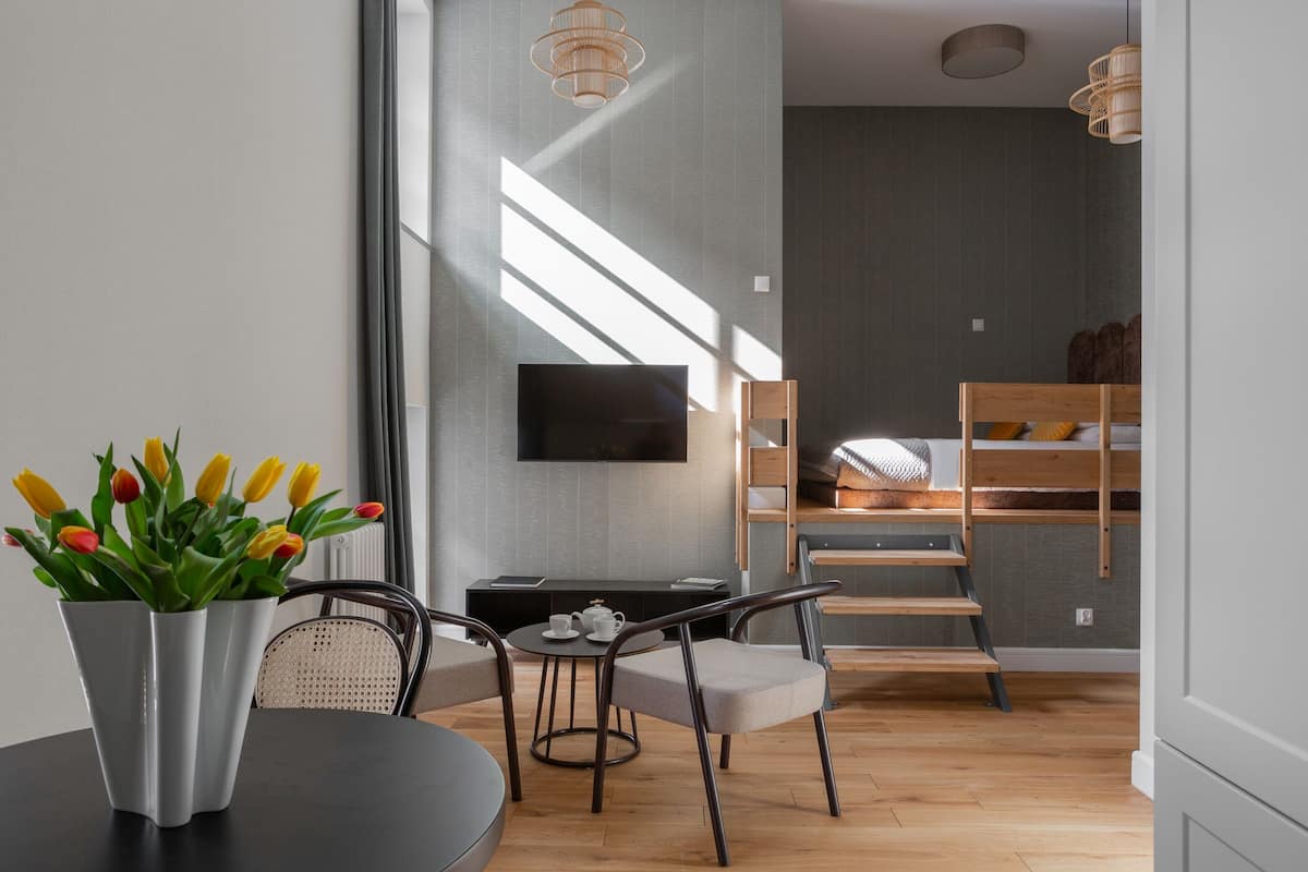 Una sala moderna con una mesa de comedor, sillas, un televisor montado en la pared y una escalera que sube a un nivel superior.