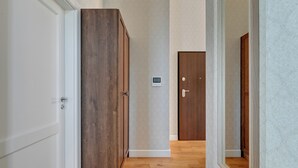 Een gang met houten deuren, een thermostaat en een houten vloer.