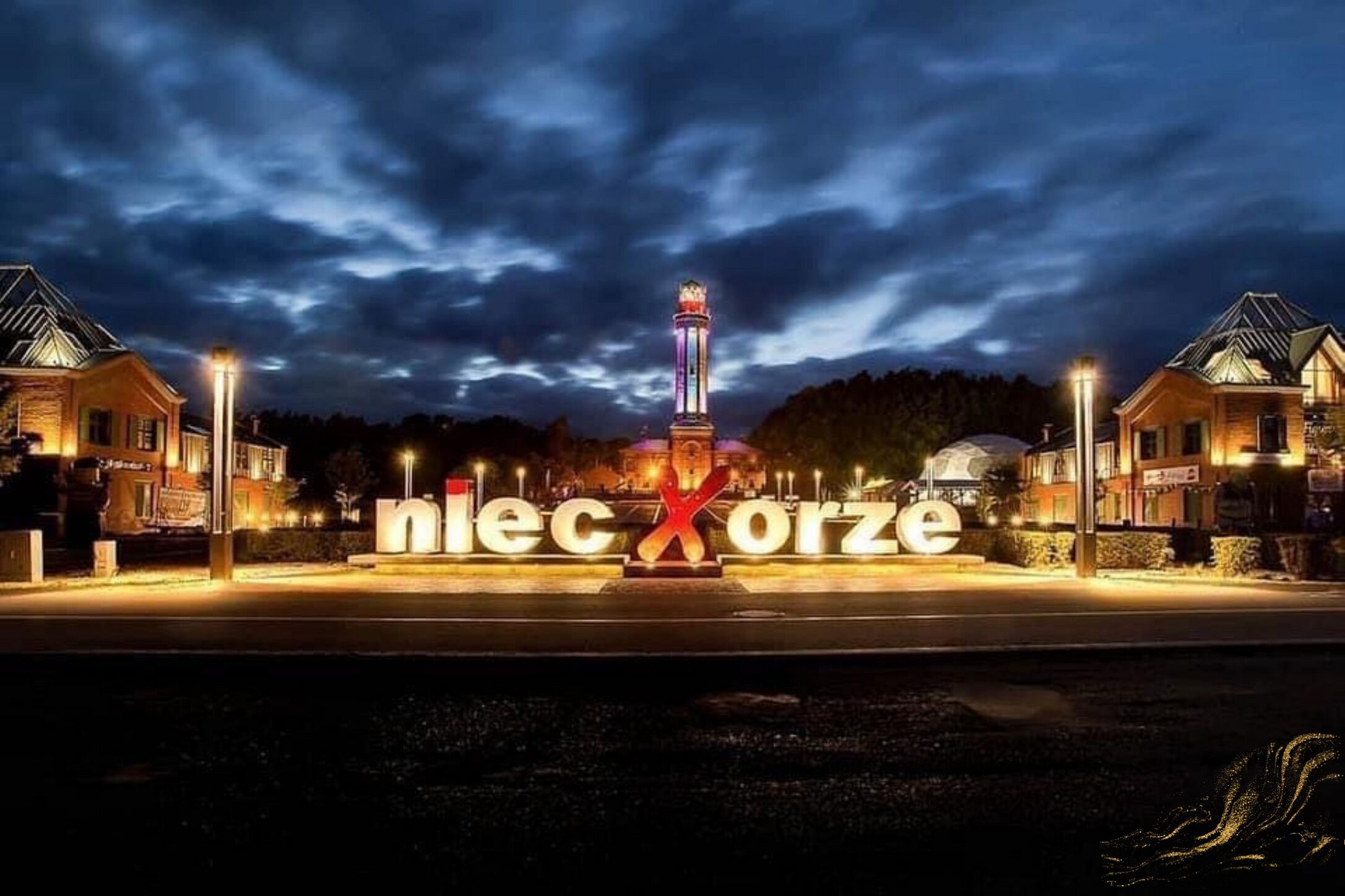 A nighttime view of a building with illuminated signage reading "nlexc orze."