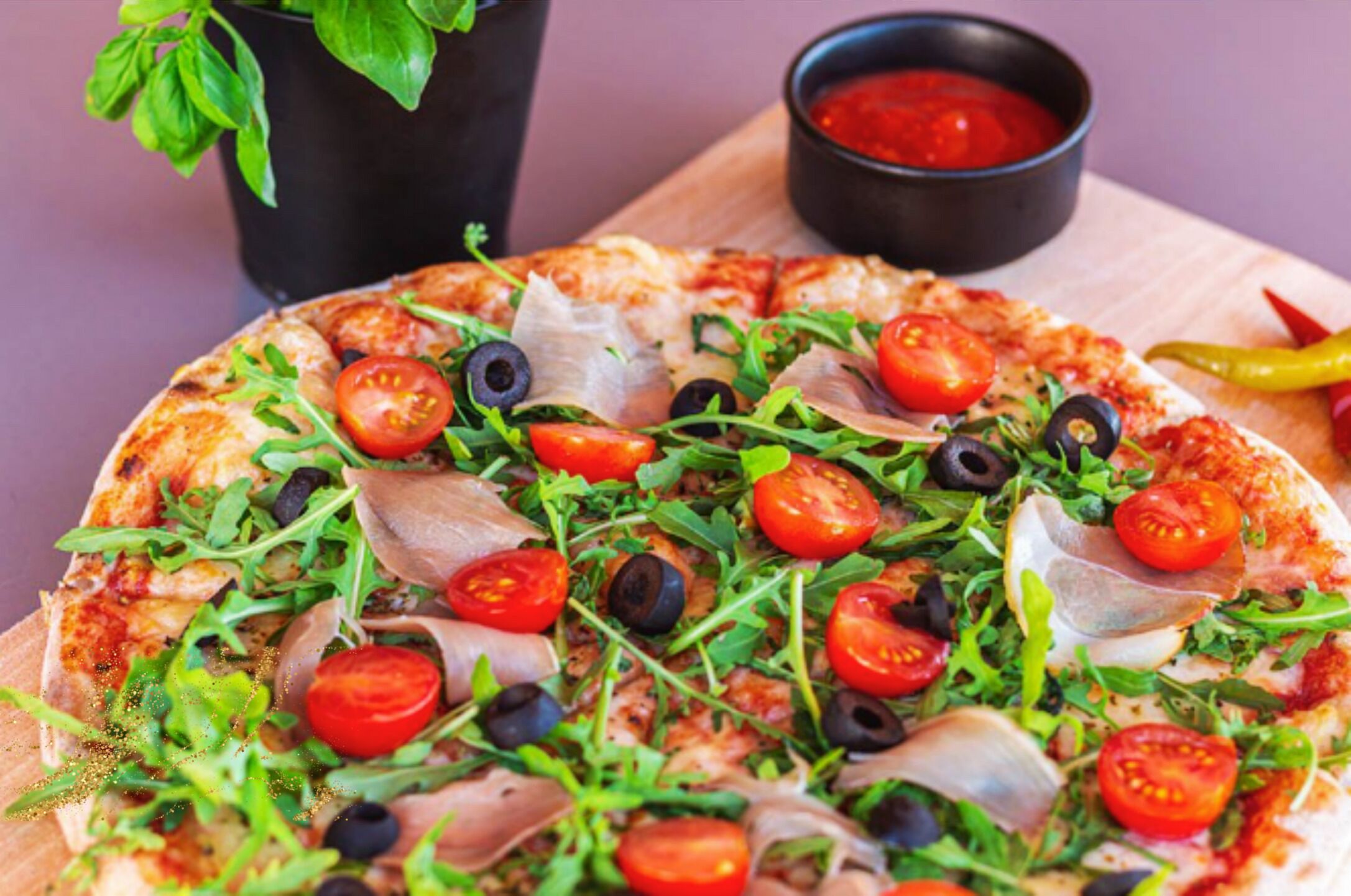 Pizza, jonka päällä on erilaisia vihanneksia ja lihaa, ja sen lisäksi tarjoillaan pieni kulho kastiketta ja paprika.