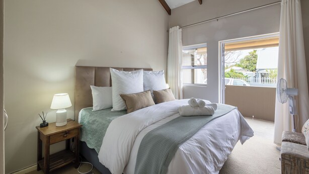 A bedroom with a bed, bedside table, lamp, and a view of the outside. - Tranquil 1-bedroom apartment in beautiful Knysna perfect for relaxing (Knysna)