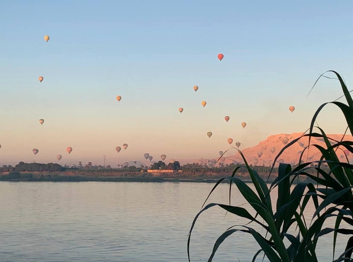 Un lac paisible, avec des montgolfières dans le ciel.