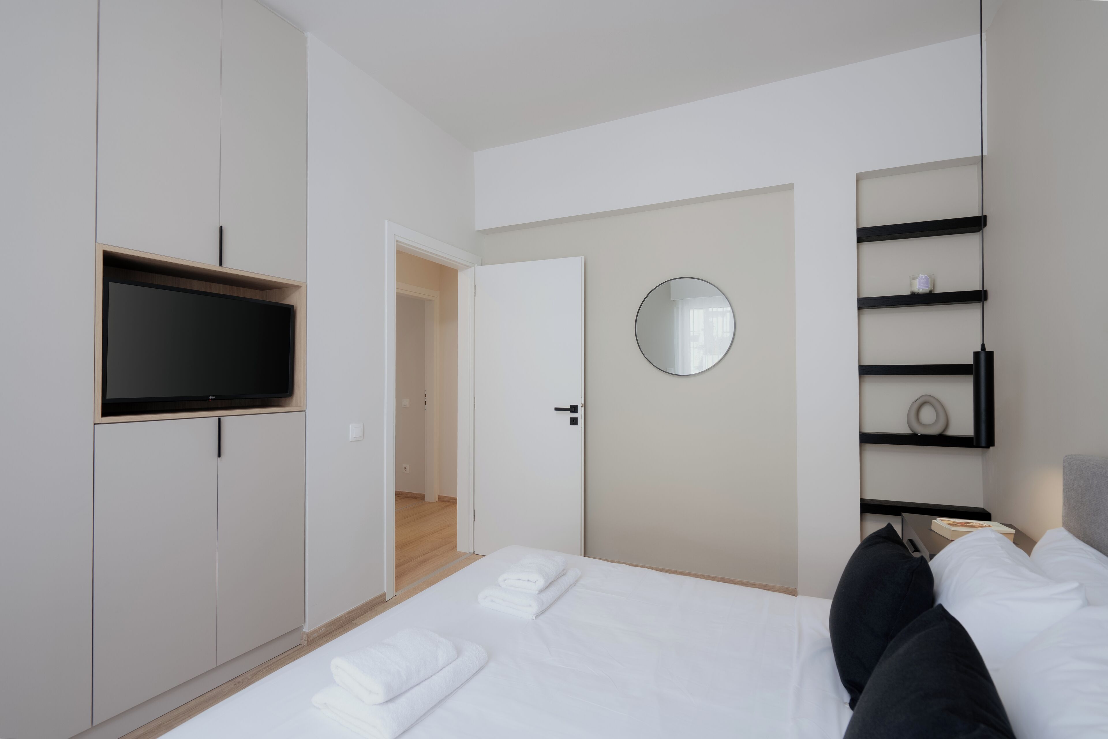 Une chambre d’hôtel moderne équipée d’un lit, d’une télévision, d’un miroir et d’une armoire.