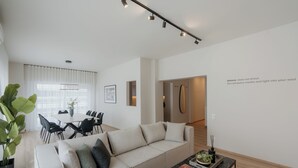 A modern living room with a sofa, coffee table, and dining area. - Luxury & Spacious Penthouse in Athens with Terrace  (Athens)