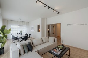 Ein modernes Wohnzimmer mit Sofa, Couchtisch und Essbereich.