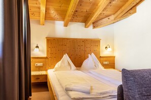 A wooden-paneled bedroom with a bed, nightstands, and wall-mounted lights. - Apartment 'Stockinger A2' with Mountain View, Shared Garden and Wi-Fi (Unterberg)