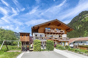 Un edificio de madera de varios pisos con balcones, un telesilla y un paisaje montañoso de fondo.