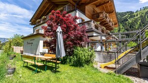 A wooden chalet with a balcony, a bench, and a slide. - Apartment 'Stockinger B4' with Mountain View, Shared Garden and Wi-Fi (Unterberg)