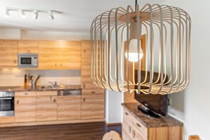 Eine moderne Küche mit Holzschränken, einer Mikrowelle und einer Pendelleuchte.