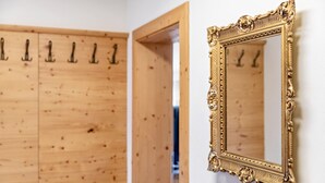A wooden wardrobe with multiple hooks and a gold ornate mirror on the wall. - Apartment 'Stockinger B4' with Mountain View, Shared Garden and Wi-Fi (Unterberg)