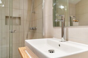 A bathroom with a white sink, chrome faucets, a mirror, and a shower area. - Apartment 'Stockinger B4' with Mountain View, Shared Garden and Wi-Fi (Unterberg)