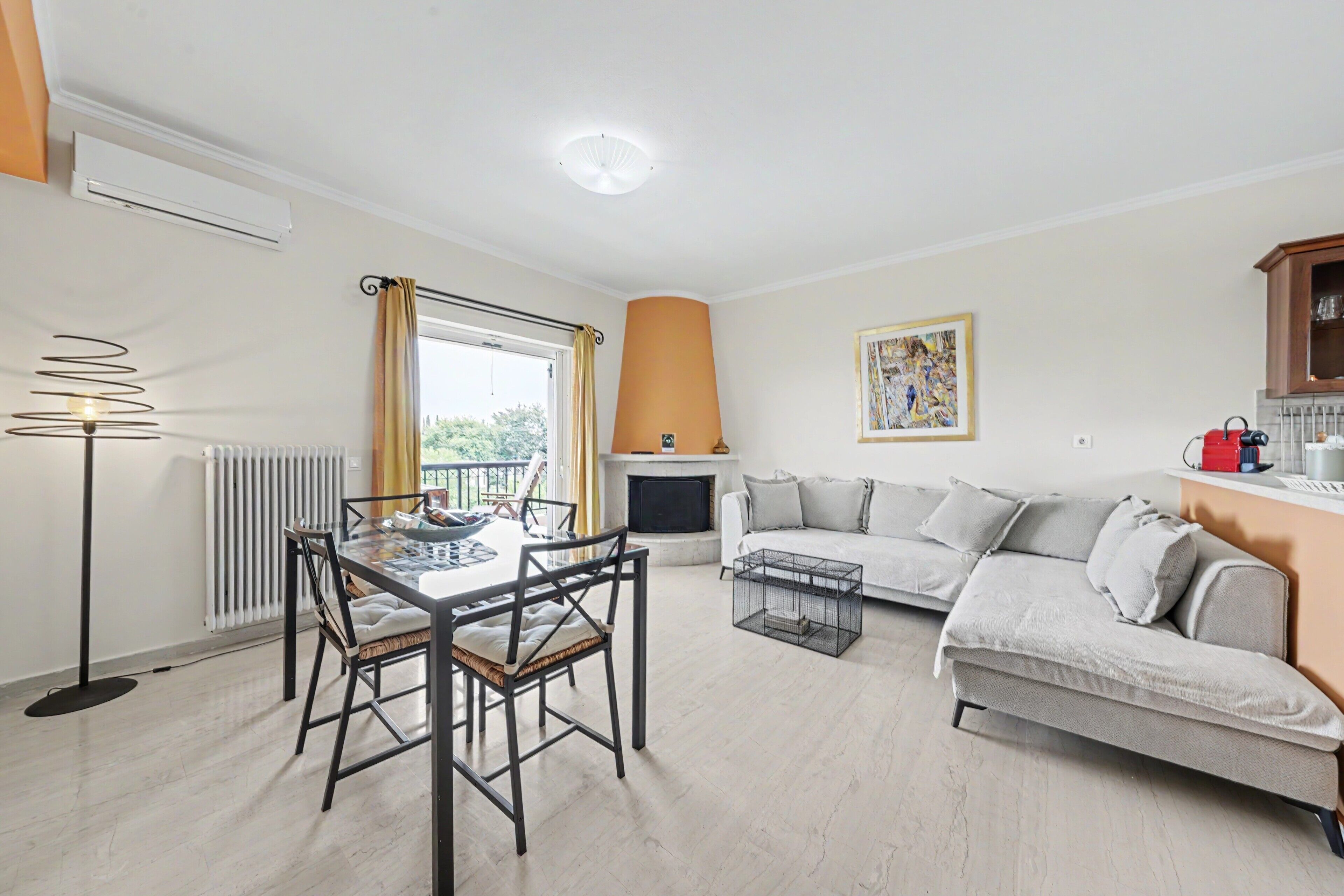 Ein Wohnzimmer mit einer Couch, einem Esstisch mit Stühlen, einem Kamin und einer Heizung.