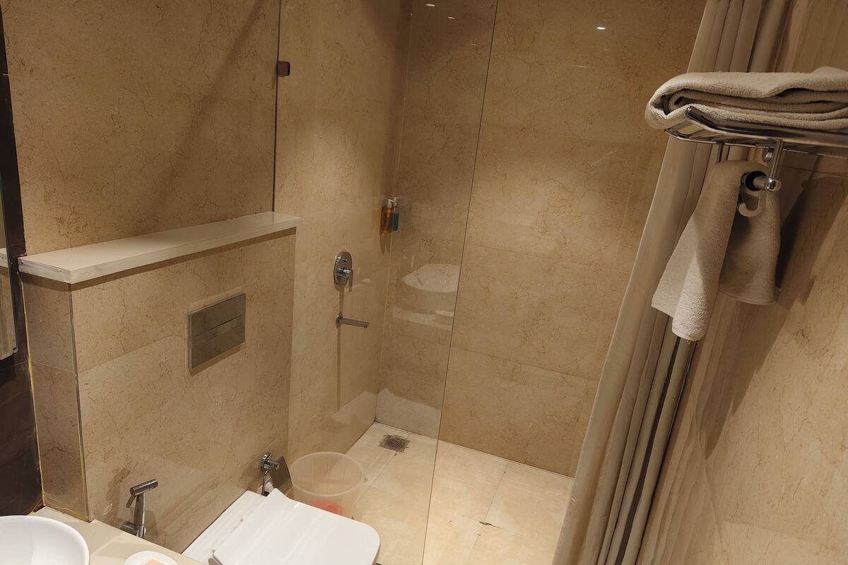 Een moderne badkamer met een douche met glazen wand, een wastafel met zeepbakje en een handdoekhouder.