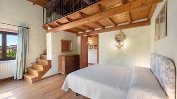 A bedroom with a wooden staircase, a bed, a dresser, and a window with curtains.